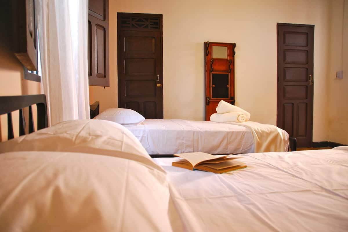 Un dormitorio con dos camas individuales, un armario de madera y un espejo en la pared.