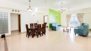 A spacious living room with a dining area, a green accent wall, and a large window with curtains. - Supun Arcade Residency (Colombo)