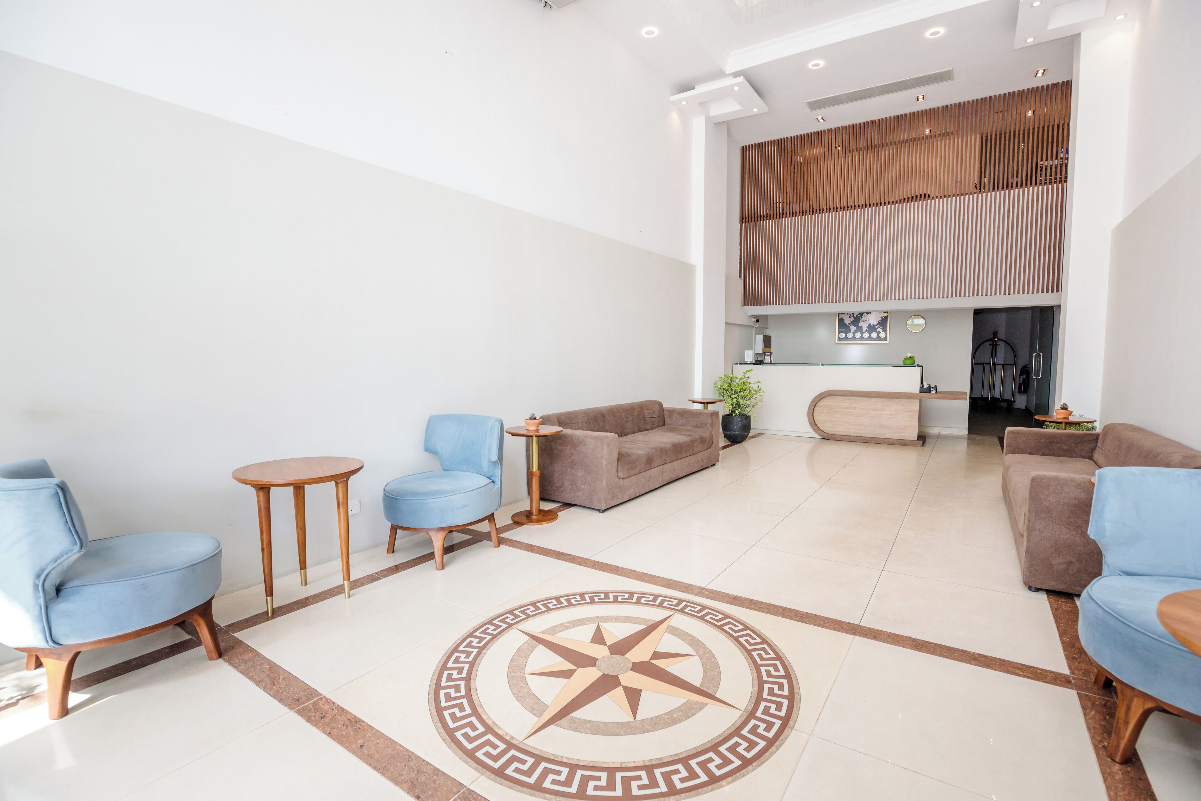 A modern lobby with a central seating area, a decorative floor pattern, and a view into a dining area.
