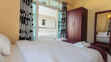 Habitació d'hotel amb un llit gran, un armari, un mirall i una finestra amb cortines.