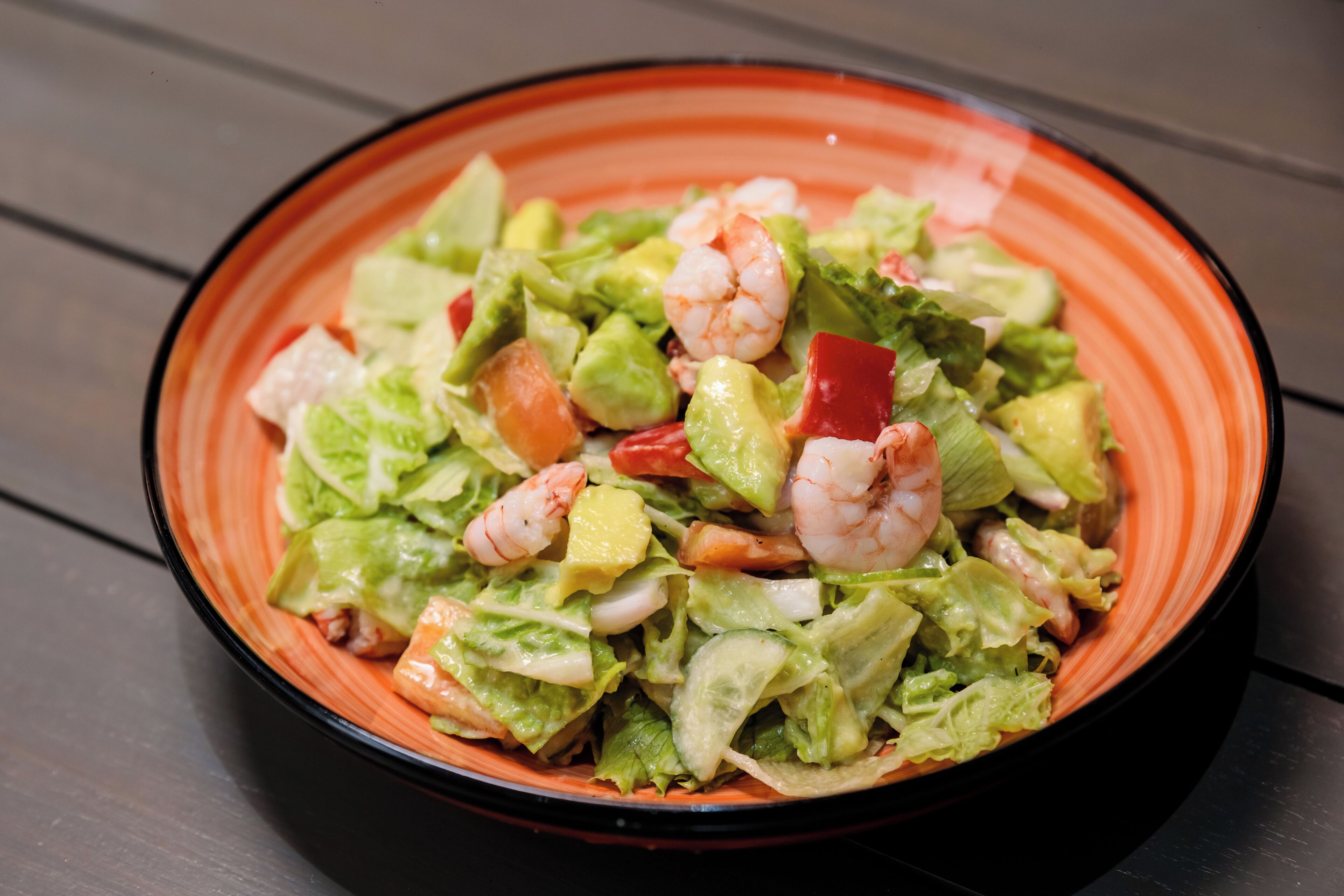 A bowl of shrimp salad with lettuce and diced tomatoes.