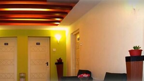 A reception area with a modern ceiling design, two doors, and potted plants on stands. - Hotel Jai (Kodaikanal)