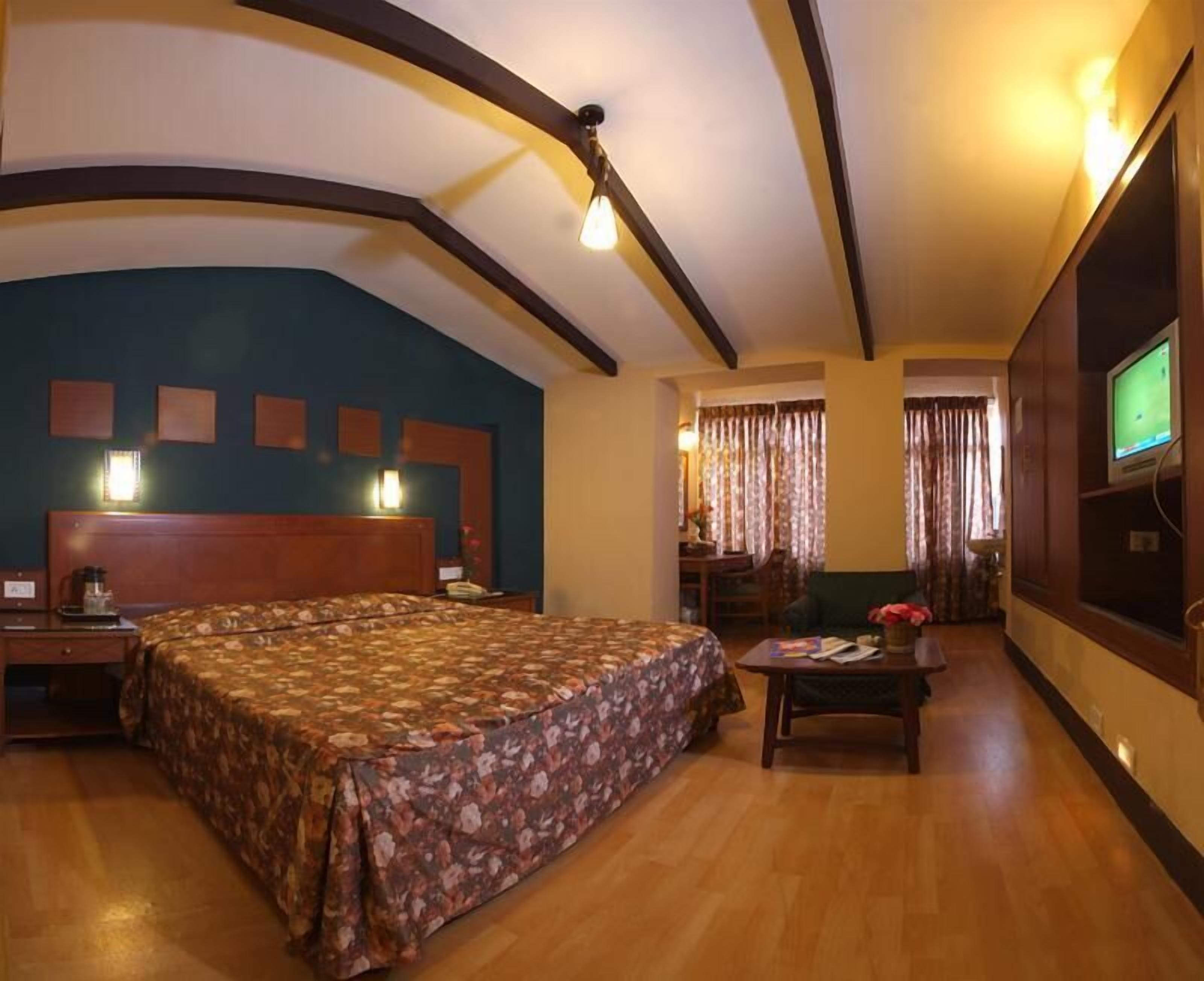 Habitación de hotel con una cama grande, un escritorio, un televisor y una ventana con cortinas.