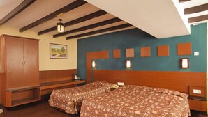 A room with two beds, wooden headboards, a wardrobe, and a painting on the wall. - Hotel Jai (Kodaikanal)