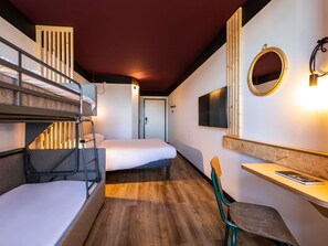 A compact hotel room with bunk beds, a desk, a chair, a TV, and a mirror.