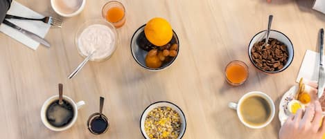 A round table with various breakfast items including bread, cereal, fruit, and beverages.