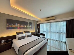 A hotel room with a large bed, a desk, a chair, a cityscape painting, and a window with curtains. - Nine Forty One Hotel (Bangkok)