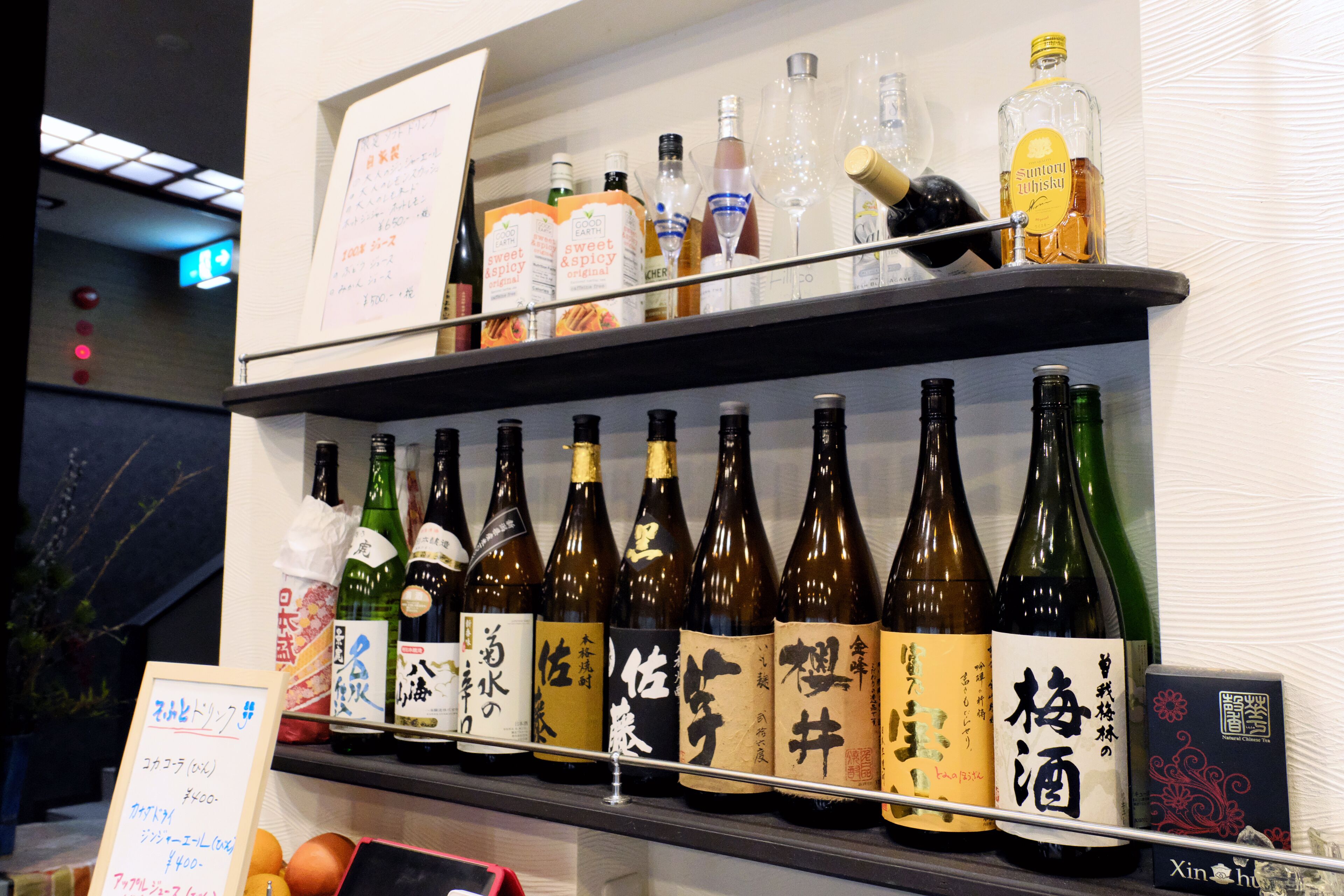 A shelf with various bottles of alcohol, including bottles with labels in a foreign script.