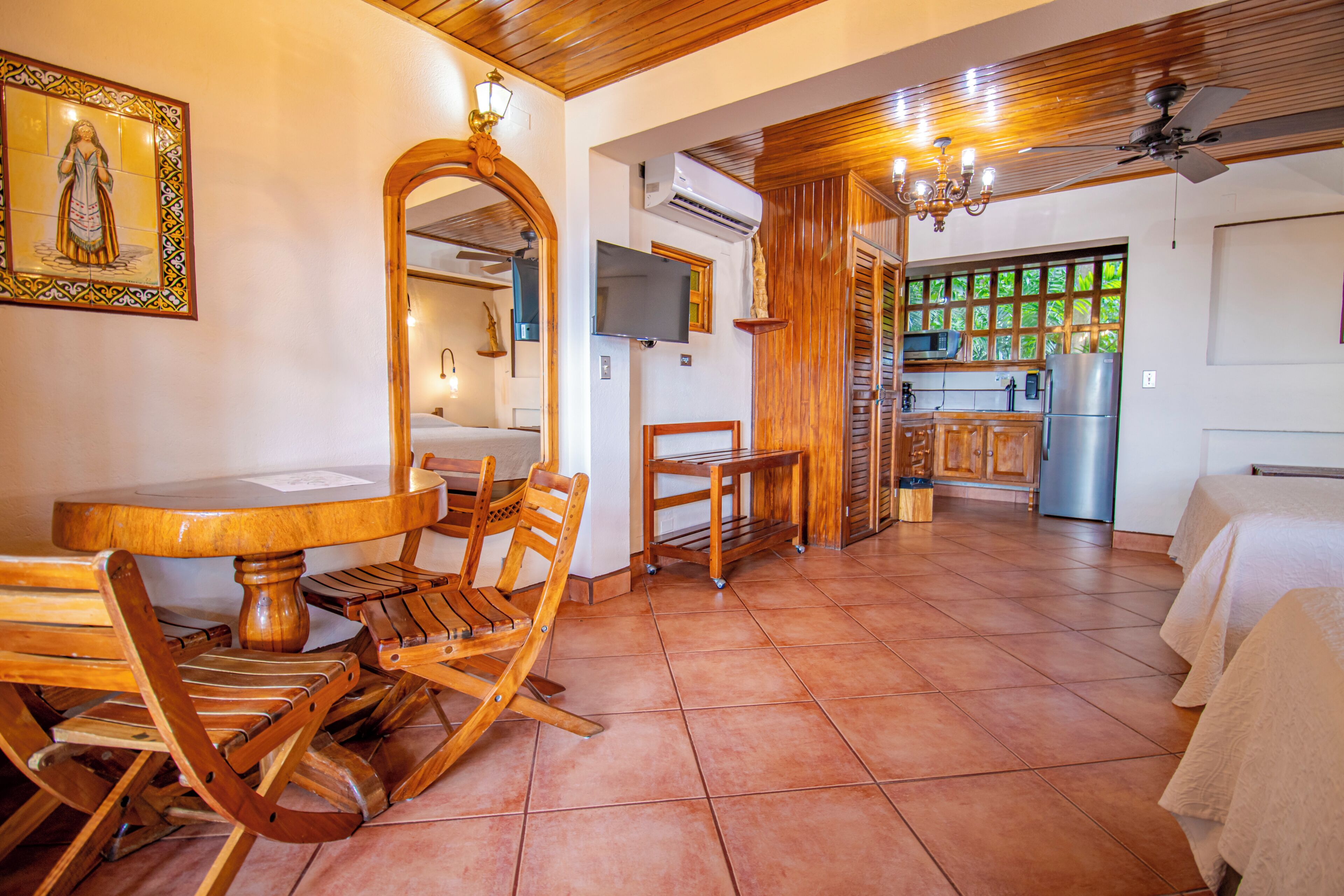 Un comedor con una mesa redonda de madera y sillas, una cocina con refrigerador y estufa, y un ventilador de techo.