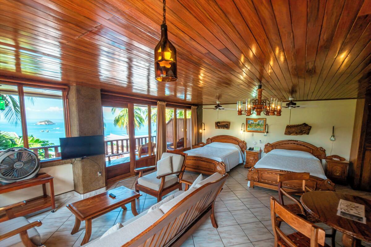 A room with wooden furniture, a bed, a sofa, a fan, and a TV.