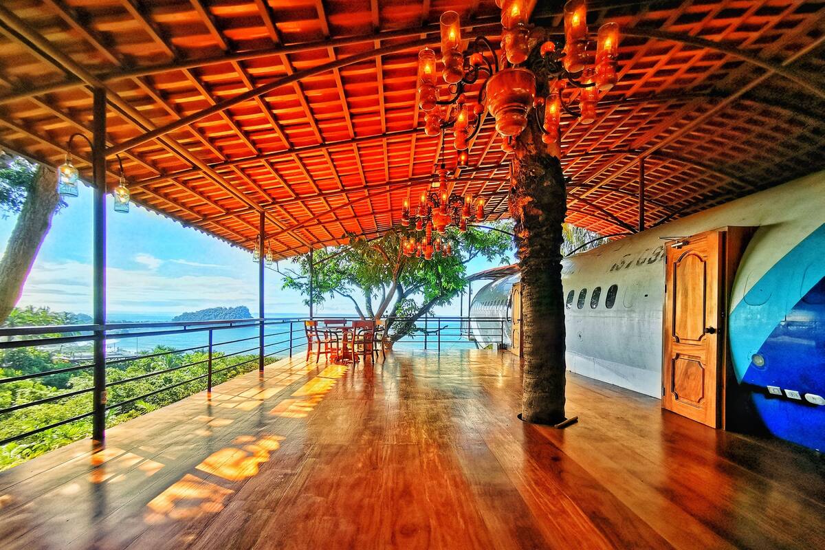 An open-air deck with wooden flooring and a ceiling of wooden beams and hanging lanterns.