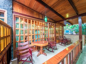 A wooden interior with a long bench, rocking chairs, and a table.