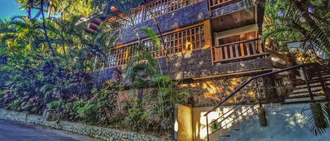 A multi-story building with a stone facade, wooden balconies, and a staircase leading to the entrance.