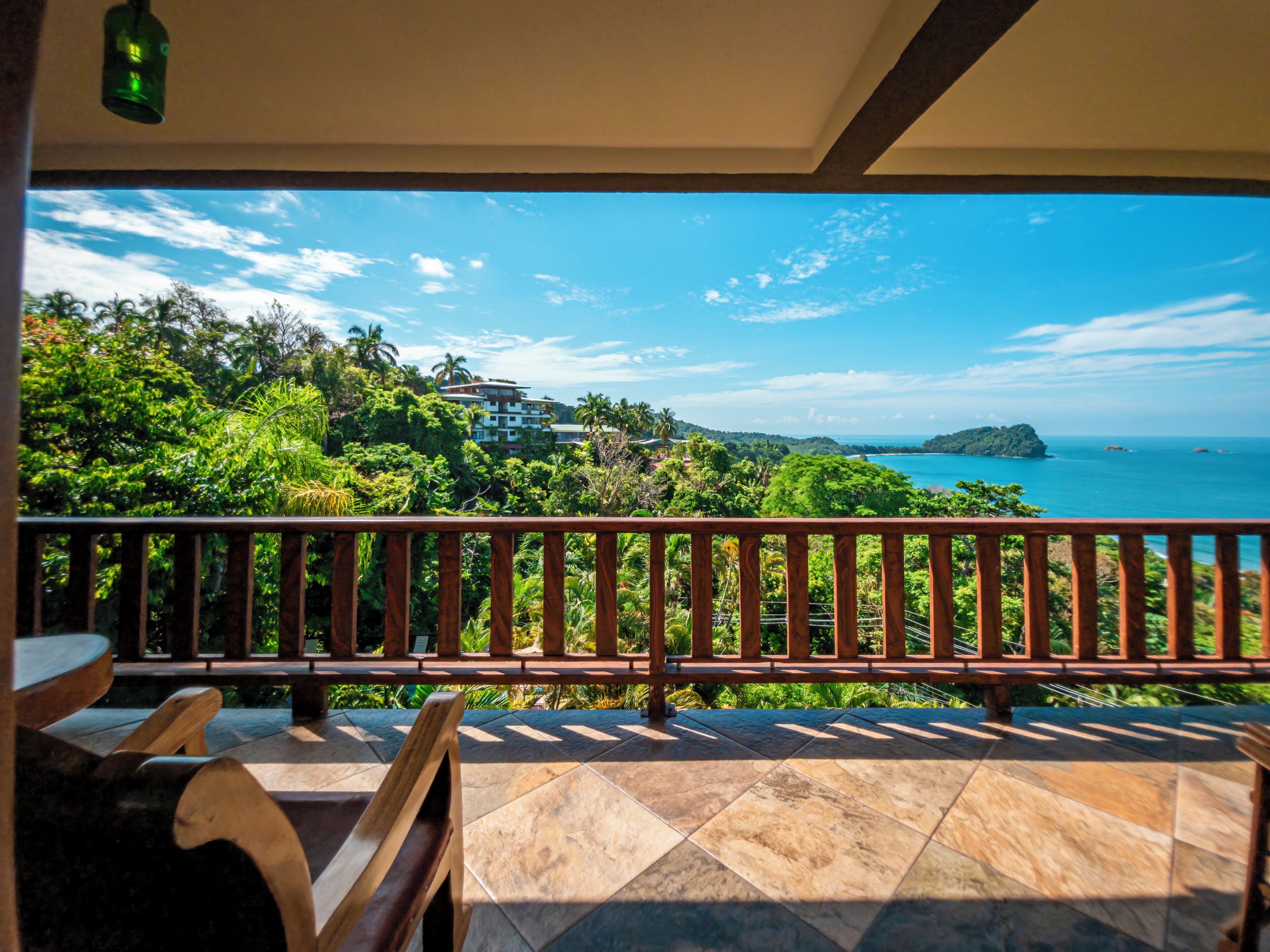 A balcony with a view of a coastal landscape, including a building and a small island.