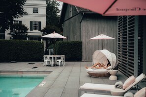 A poolside area with lounge chairs, umbrellas, and a small table.