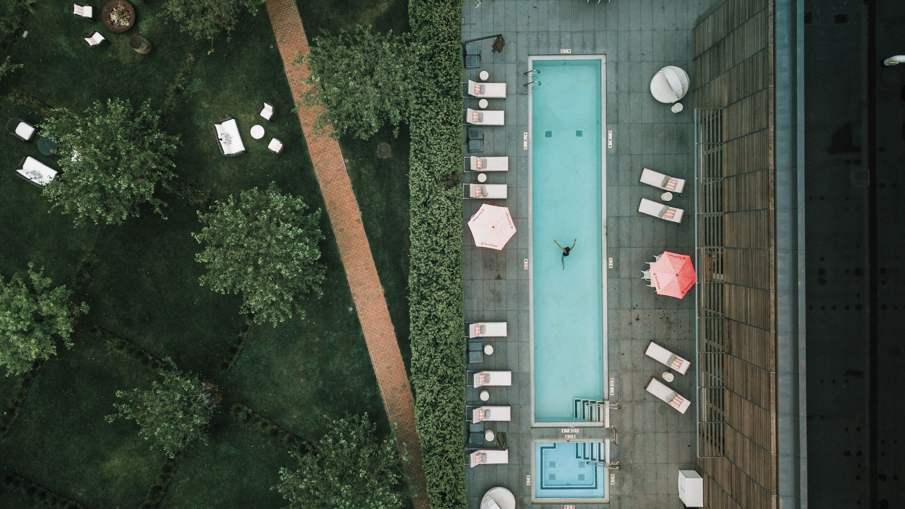 Vista aérea de uma área de piscina com espreguiçadeiras e guarda-sóis.
