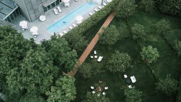 An aerial view of a modern building with a swimming pool, outdoor seating, and a well-maintained garden.