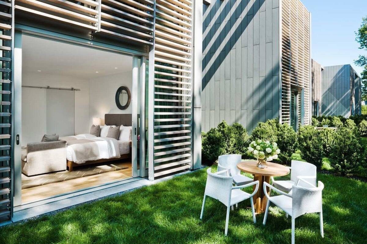 A modern hotel room with a bed, bedside table, and a view of the garden.