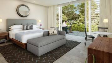 A modern hotel room with a bed, a sofa, a dining table, and a view of the outdoors.