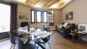 Una sala moderna con una mesa de comedor de vidrio, un sofá de cuero negro y techo de madera.