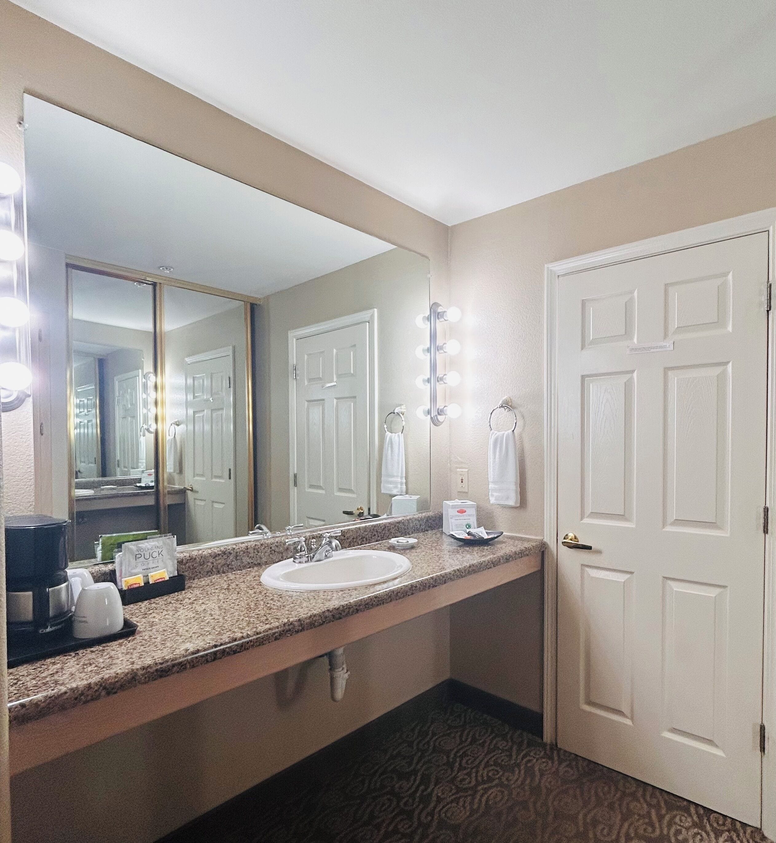 Un bagno d'hotel con lavandino, specchio e luci sopra il mobile.