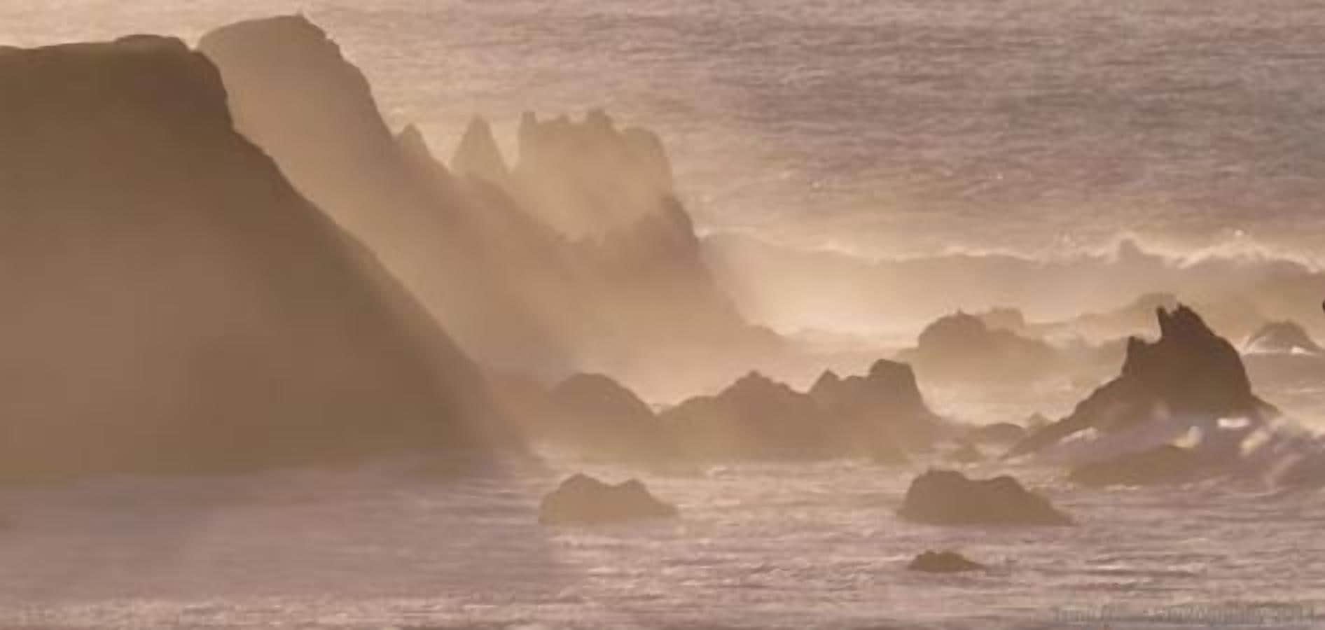 A coastal scene with large rock formations and waves.
