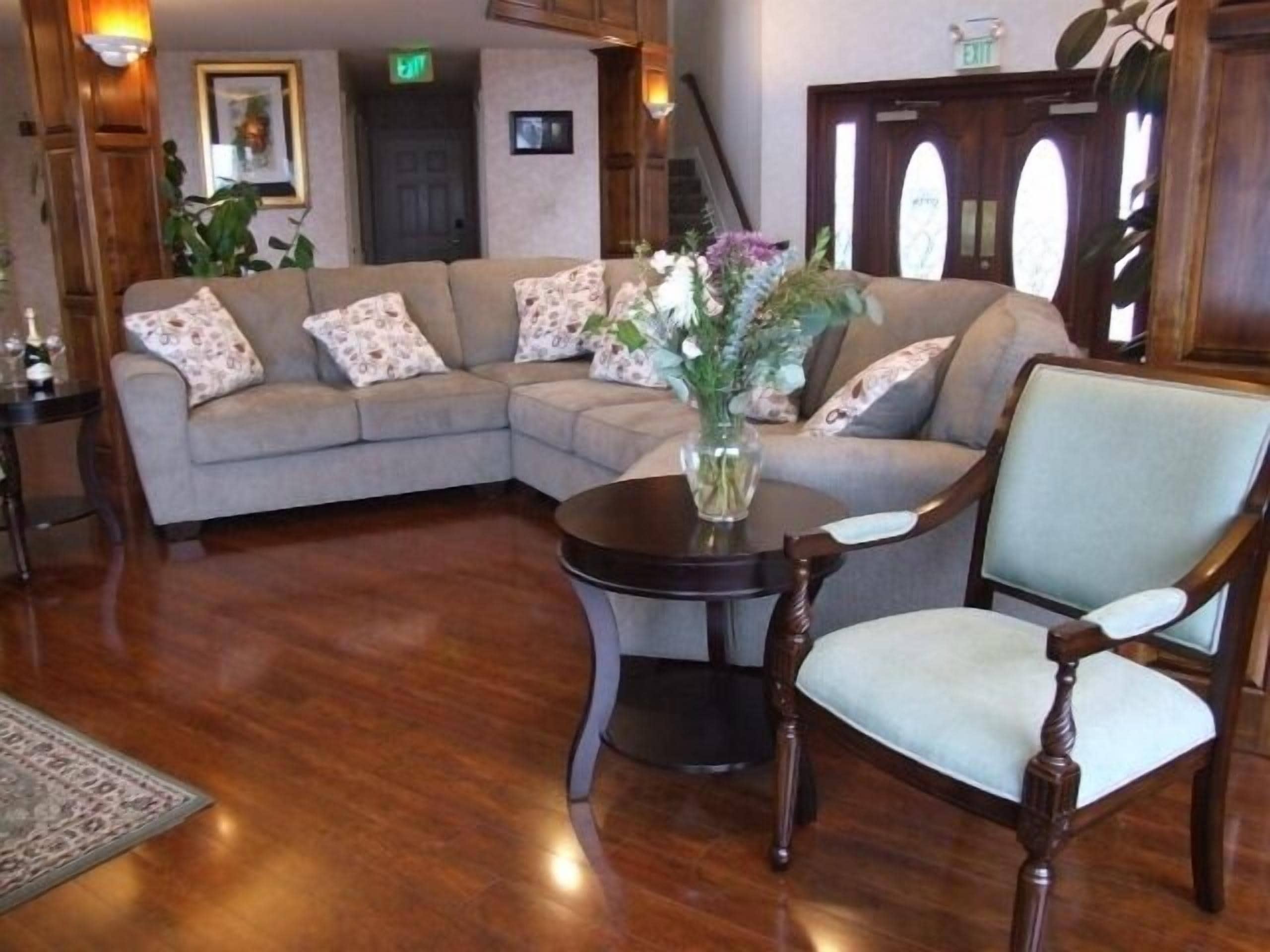 A living room with a sectional sofa, a round wooden table, and a classic wooden chair.