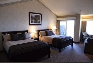 A hotel room with two beds, a desk, a chair, and a large window. - North Cliff Hotel (Fort Bragg)
