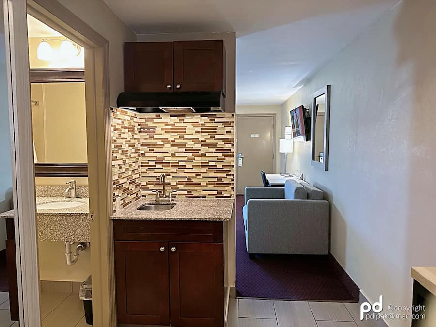 A compact kitchen with a tiled backsplash, a sink, and wooden cabinets.