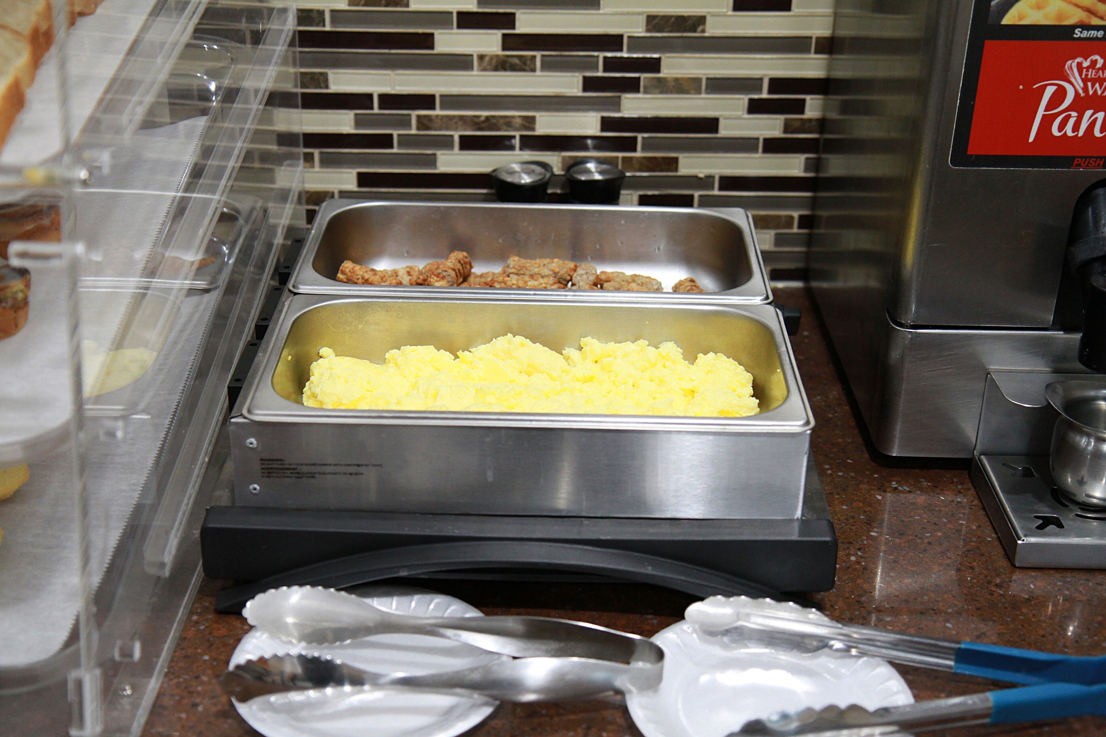A buffet setup with trays of food, including rice and meat, and a coffee machine.