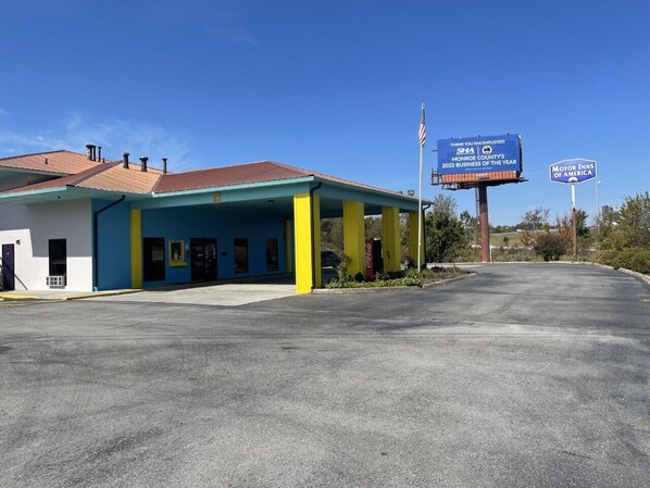 A building with a blue and yellow facade, a Coca-Cola sign, and a parking lot.