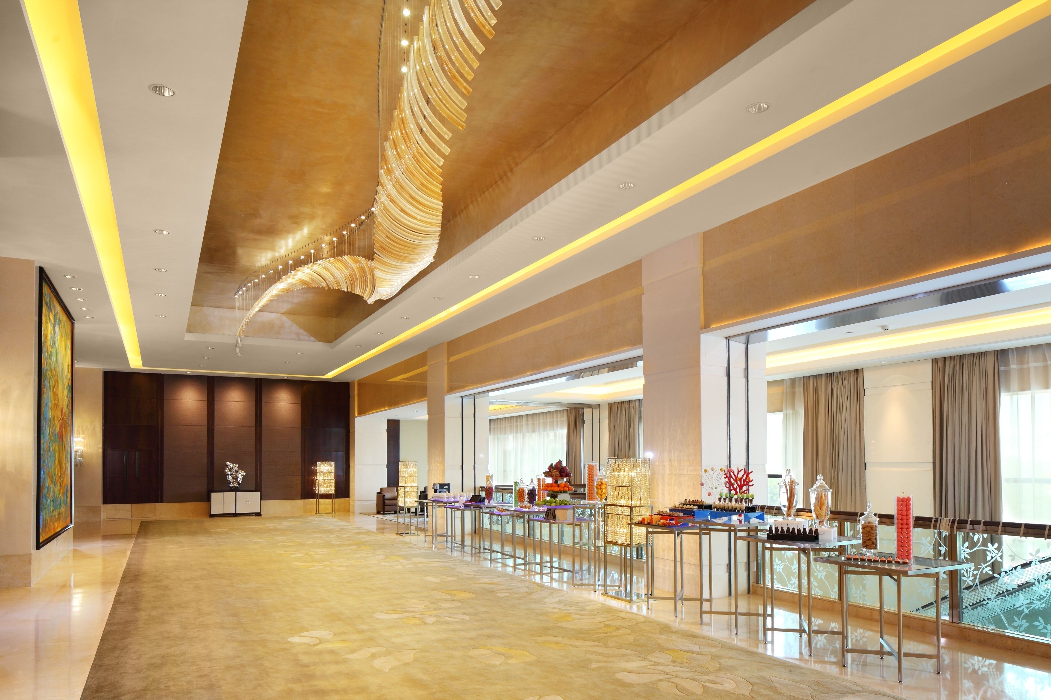 Un hall d’entrée spacieux, doté d  ’un sol en marbre, d’un long comptoir de réception et d’un lustre moderne.