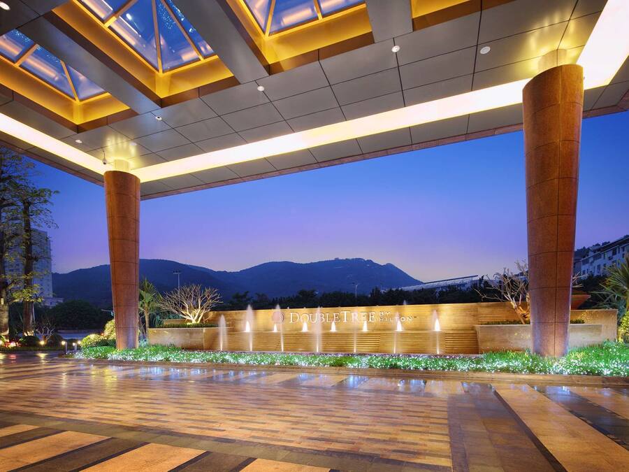 Un amplio espacio al aire libre con una fuente, columnas grandes y vistas a montañas al fondo.
