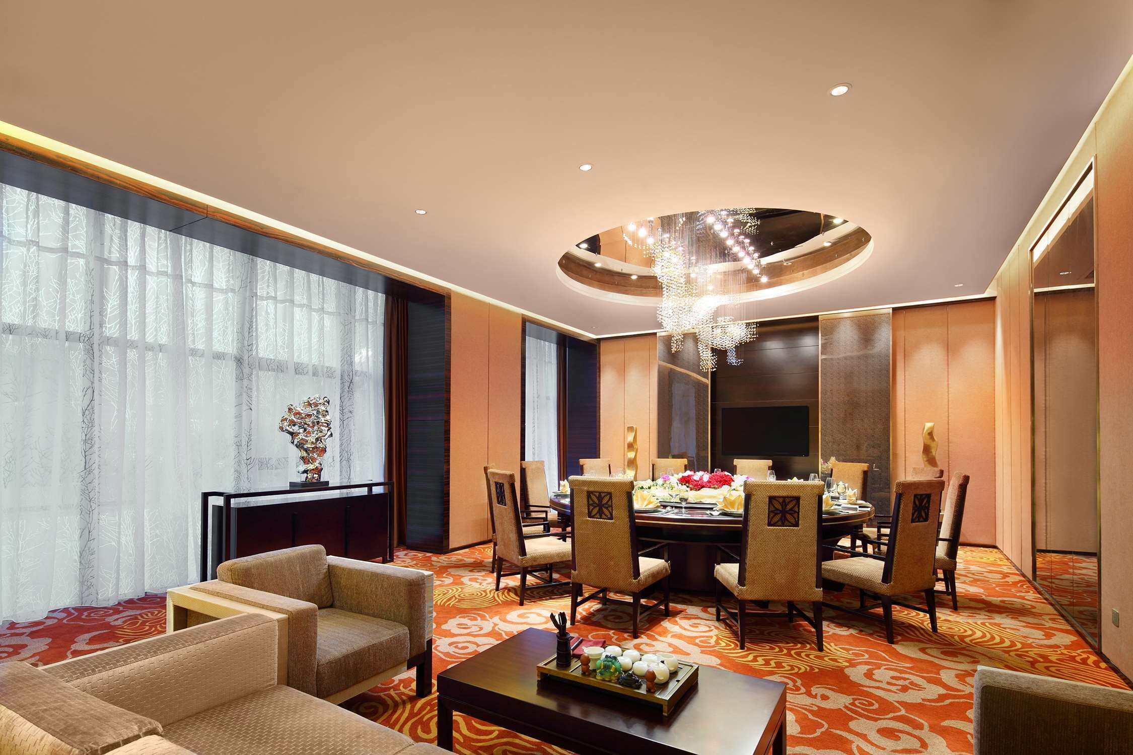 A hotel room with a dining area, large windows, and a chandelier.