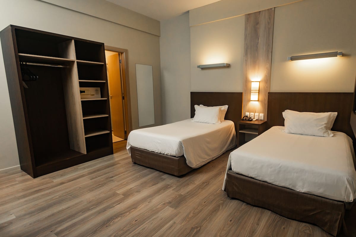 Ein Hotelzimmer mit zwei Betten, einem Kleiderschrank und einem Spiegel.