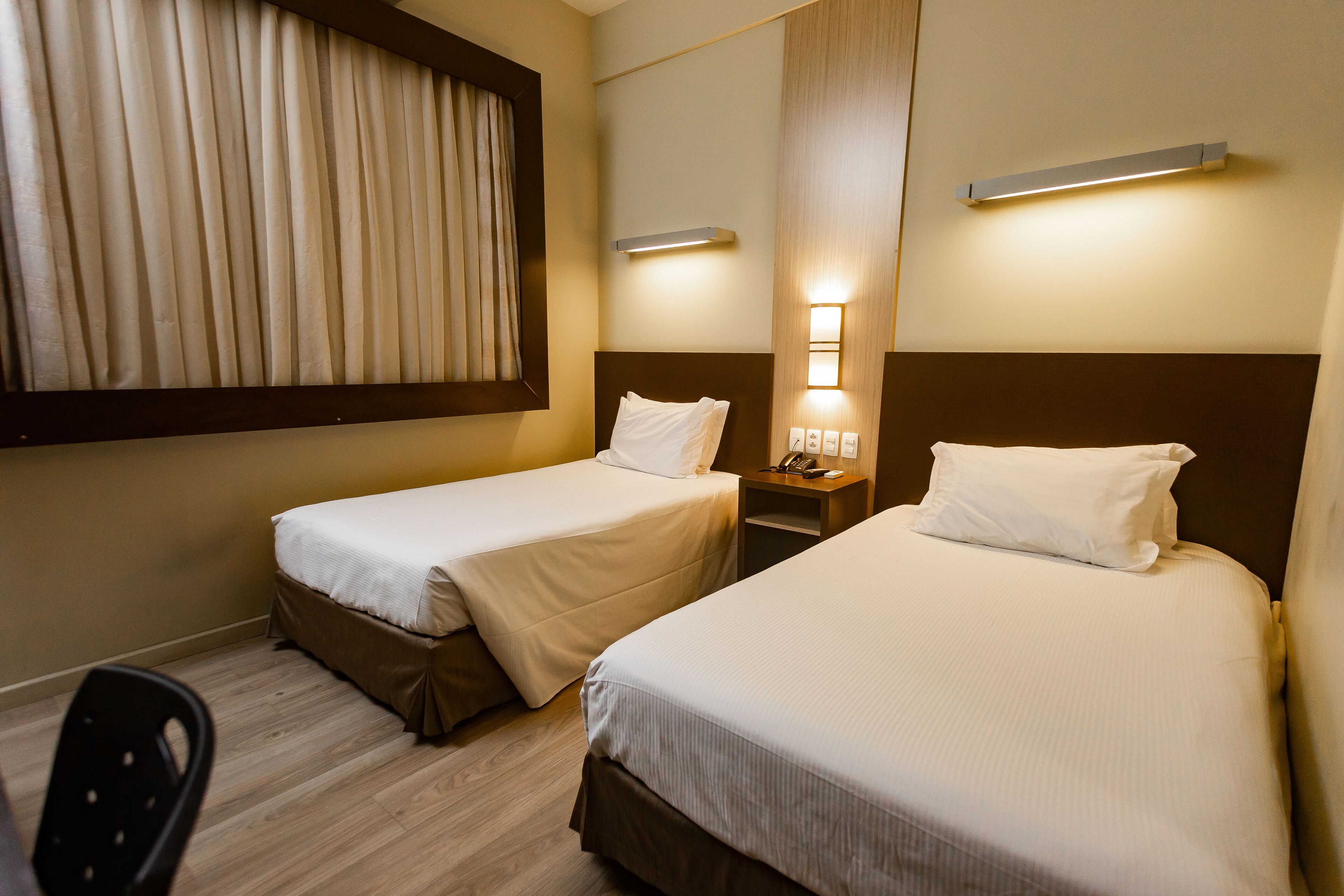 Ein Hotelzimmer mit zwei Betten, einem Schreibtisch und einem Stuhl.