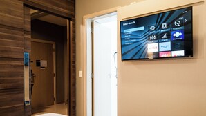 A hotel room with a mounted TV displaying various streaming services and a wooden door.