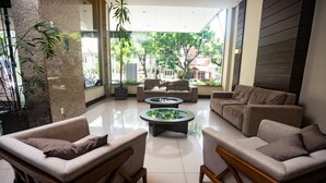 A modern living room with a glass coffee table, two sofas, and a large window offering a view of the city.