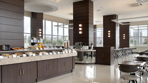 A modern kitchen with a long counter, built-in appliances, and a view of the city.
