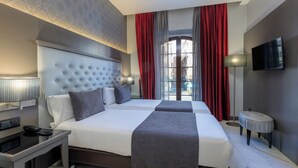 A hotel room with a large bed, a bedside table with a lamp, a TV, and a window with curtains. - Hotel Ciutadella Barcelona (Barcelona)