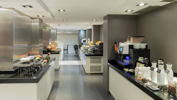 Una cocina moderna de hotel con electrodomésticos de acero inoxidable, una zona de buffet y una estación de café.