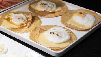 Una bandeja con huevos Benedictos, jamón y salsa holandesa sobre tostadas.