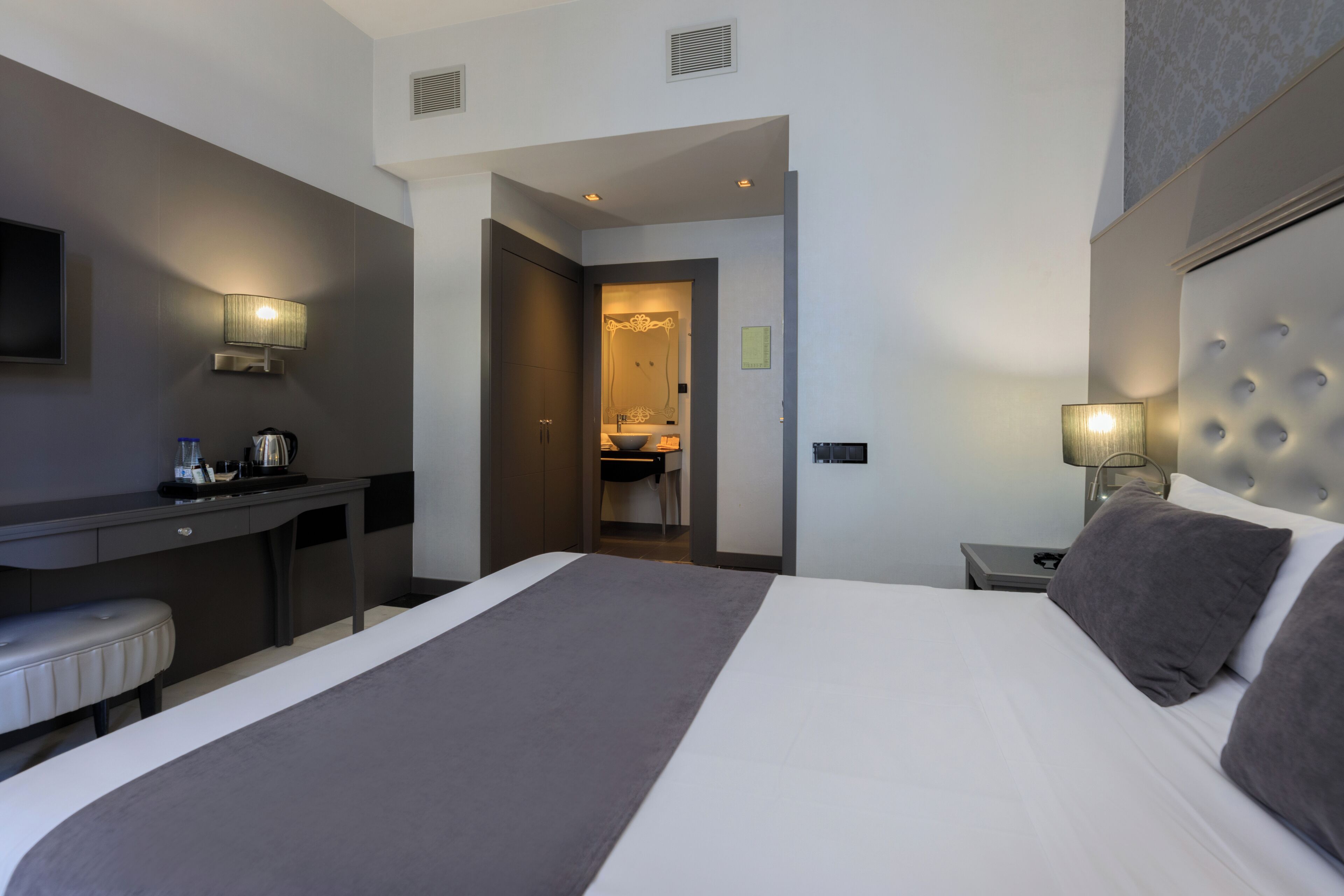 Une chambre d’hôtel moderne avec un grand lit, un bureau et une télévision.