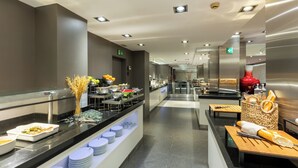 A modern hotel breakfast area with a buffet setup, including various food items and utensils. - Hotel Ciutadella Barcelona (Barcelona)