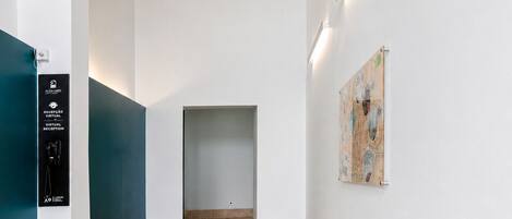 A hallway with a reception desk, a wall-mounted artwork, and a ceiling with a geometric pattern.