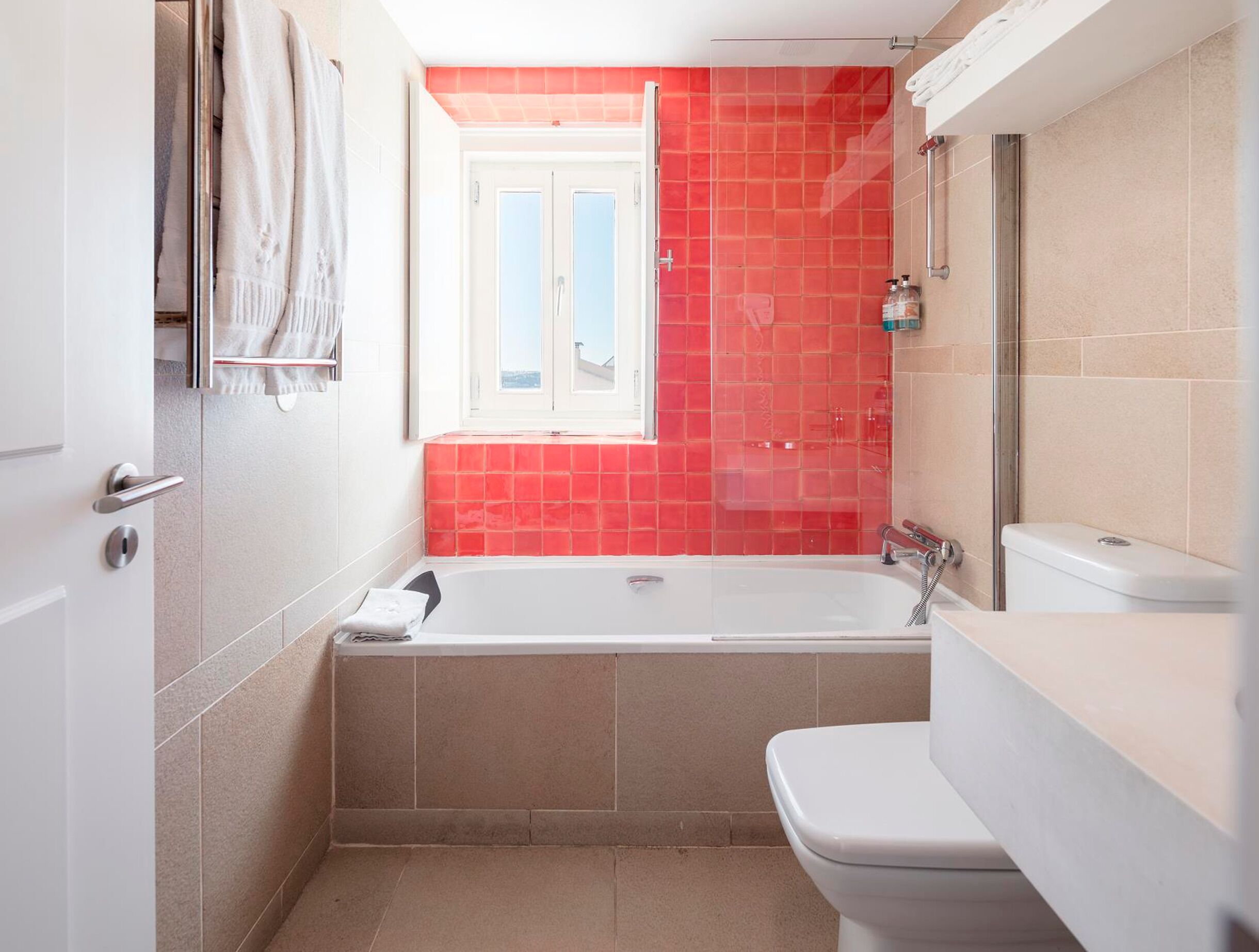 A bathroom with a bathtub, toilet, and a window with a view.