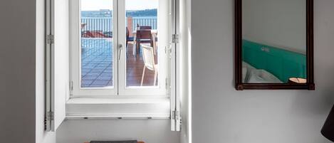 A room with a view of a terrace, a wooden chair, and a mirror on the wall.