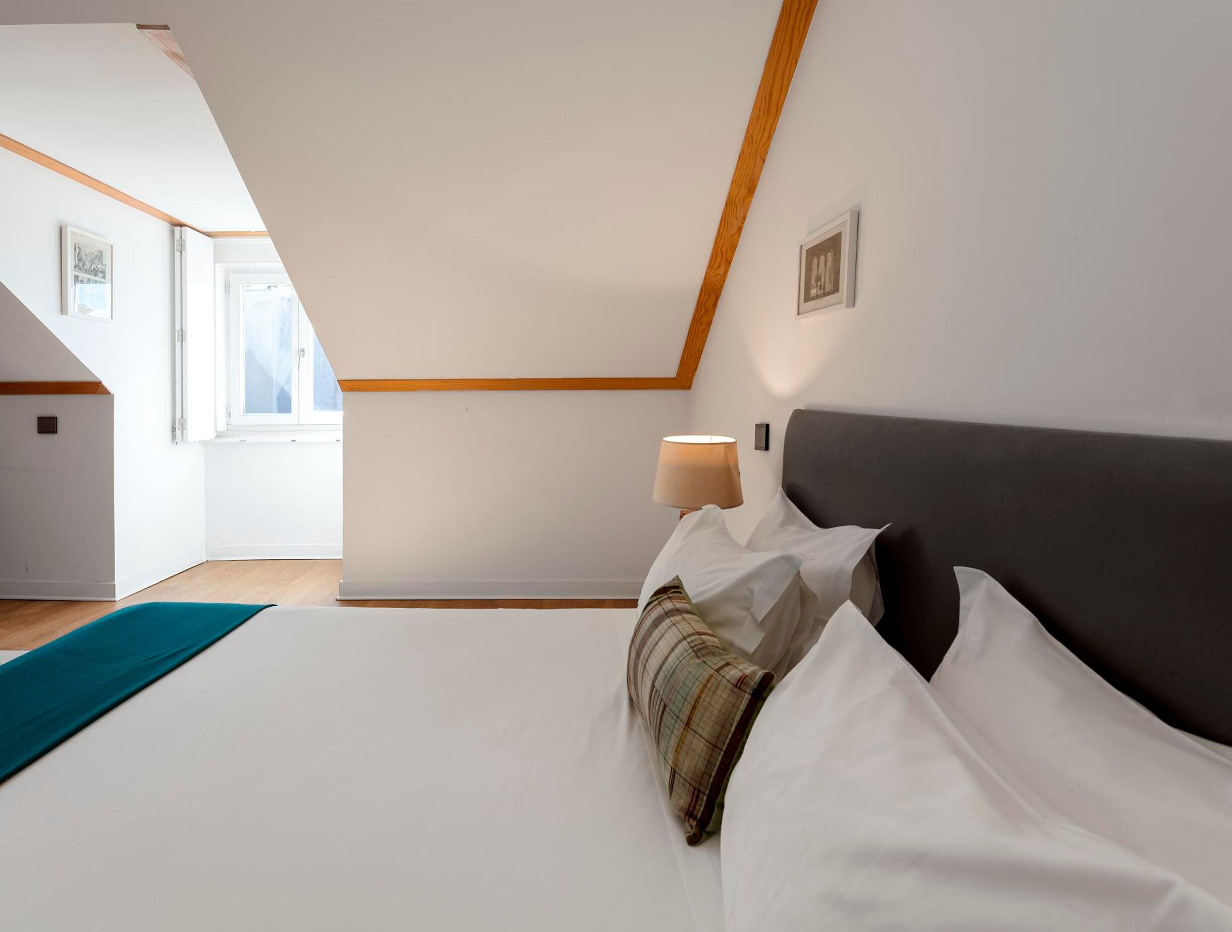 A bedroom with a bed, a lamp, a window, and a view of the outside.