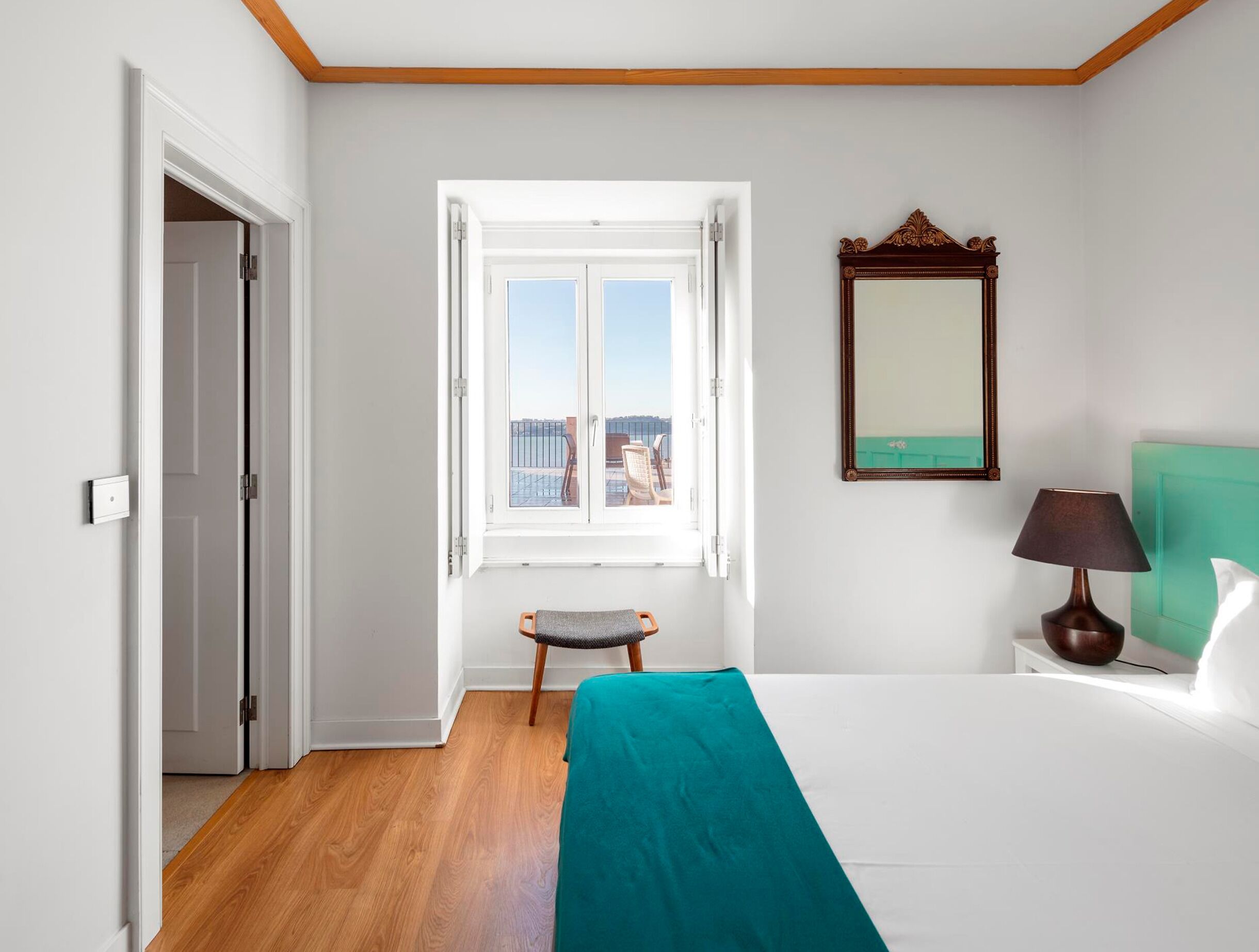 Ein Hotelzimmer mit Bett, Fenster mit Blick, Spiegel und Nachttisch.