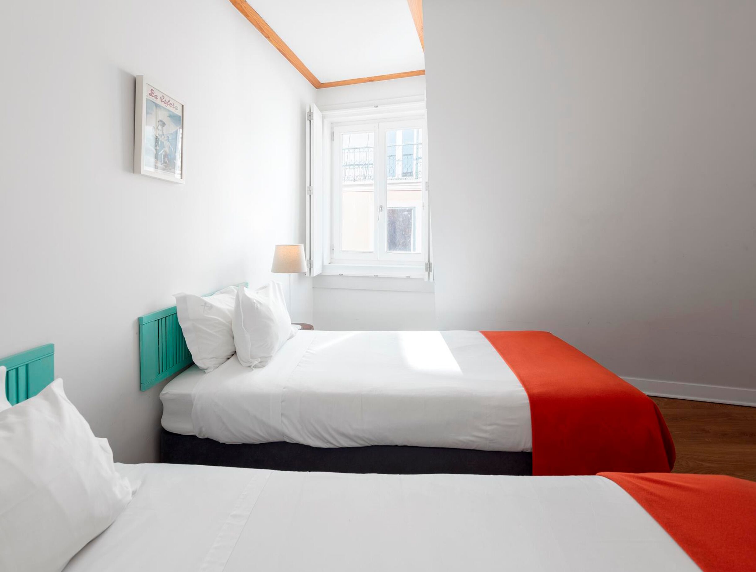 Ein Schlafzimmer mit zwei Betten, einem Fenster und einem gerahmten Bild an der Wand.